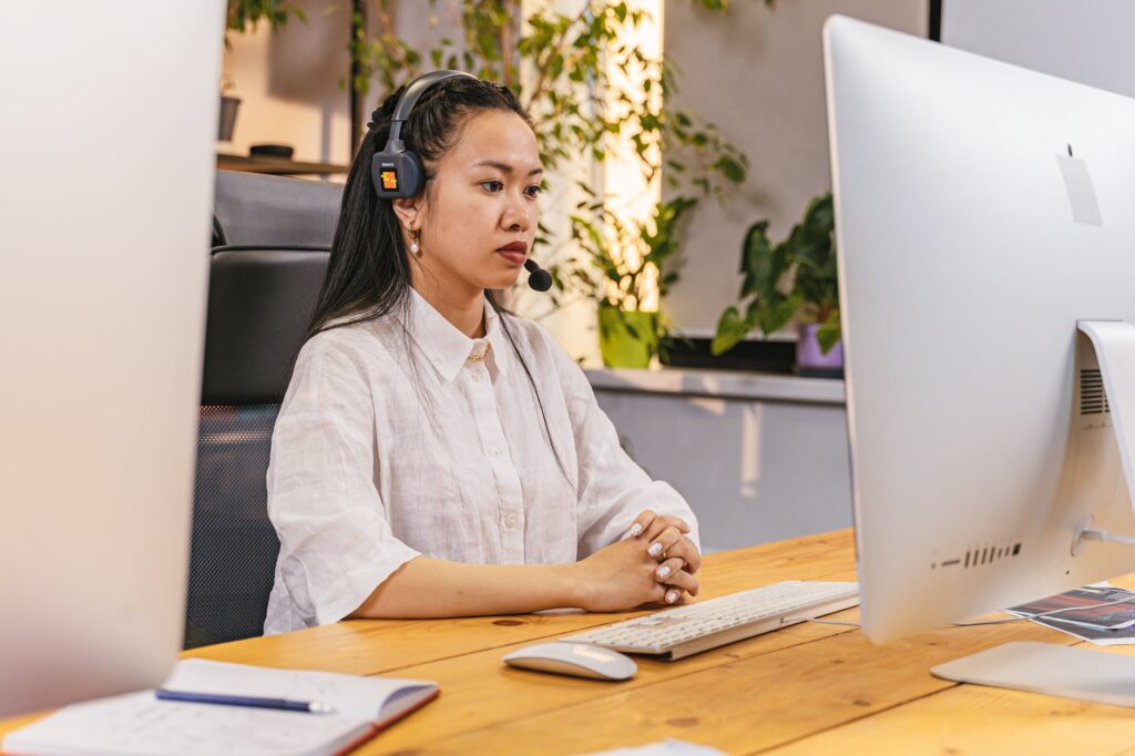 woman with headphones and mic working in an office on computer
